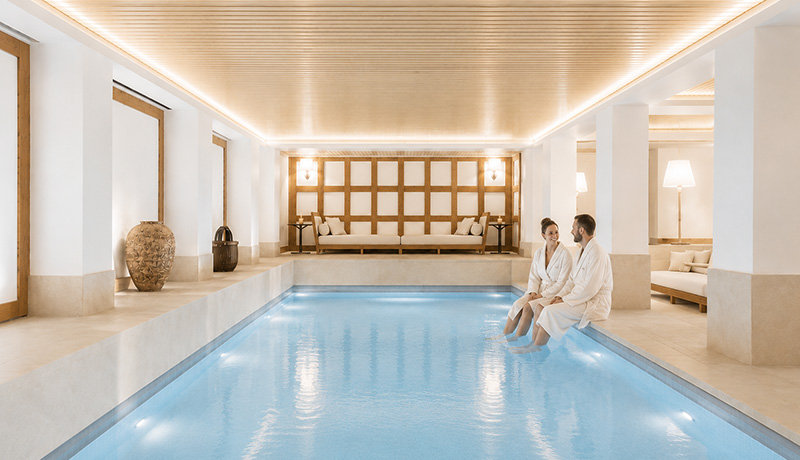 Couple en peignoir au bord d’une piscine intérieure dans le spa d’un chalet de luxe des Alpes françaises